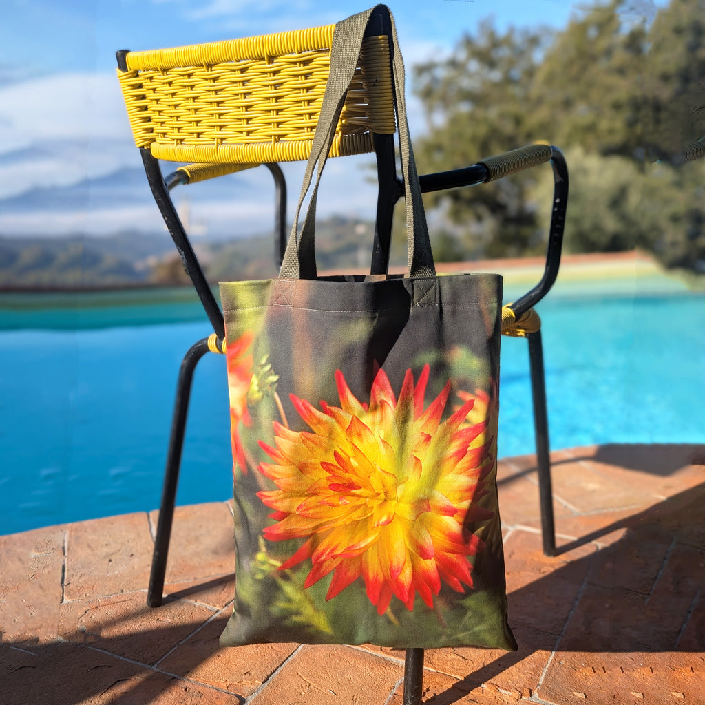 Orange dahlia cotton tote bag hanging on a chair beside a pool – floral print bag made in the UK.
