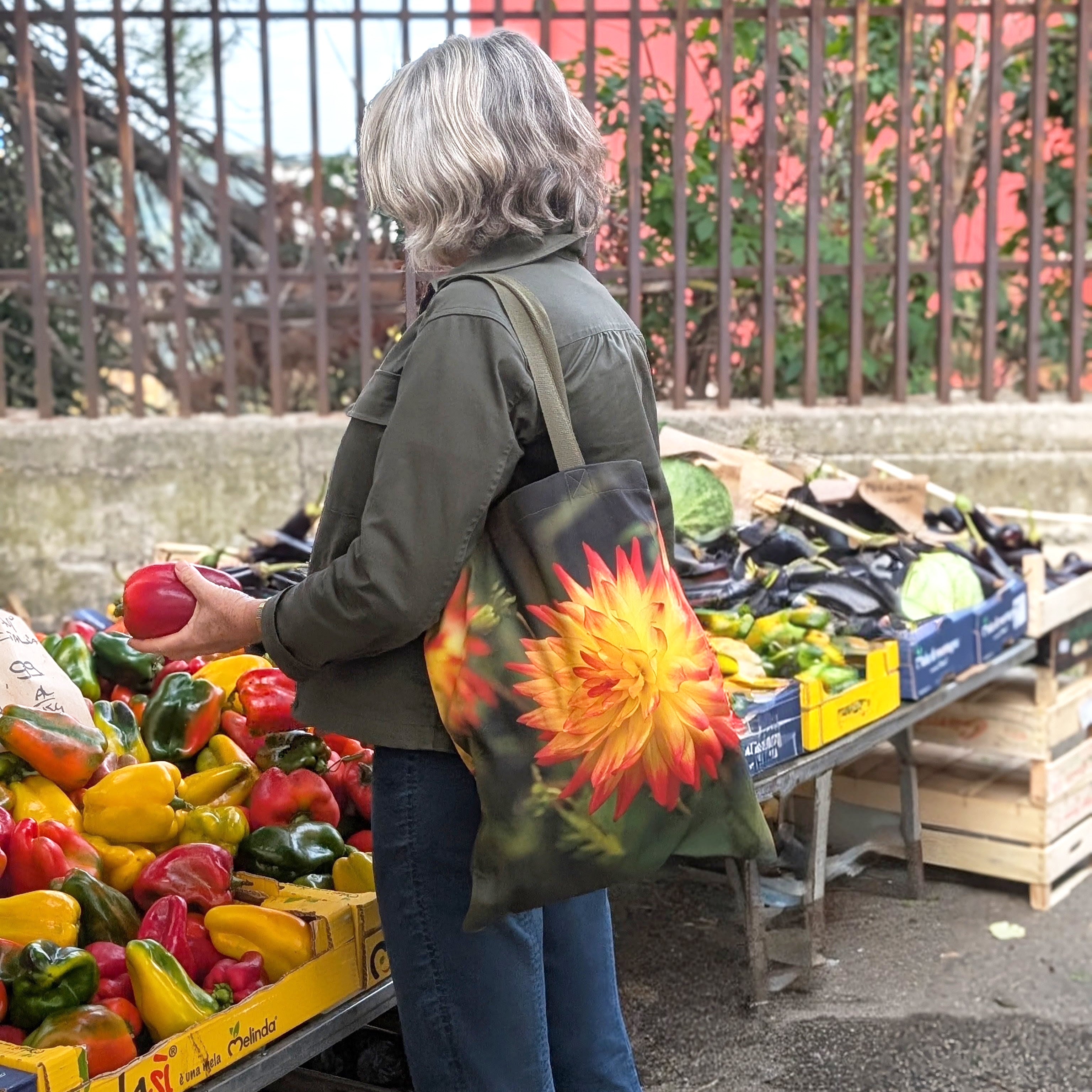 Bright orange dahlia print tote  in use at an outdoor market in Italy